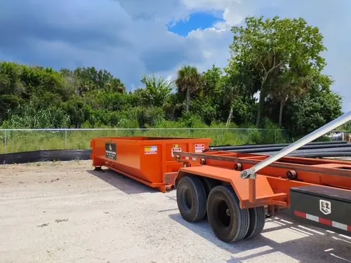 Orange Champs dumpster beside the roll off trailer bed on the Winter Park yard