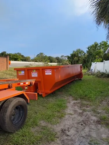 Rear view of the orange Champs dumpster on the Paisley field by the white fence line