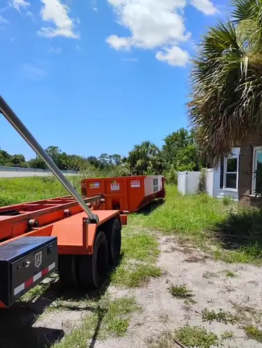 Champs dumpster set across a grassy Paisley lot with the trailer pulled up alongside