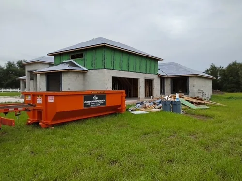 Orange Champs dumpster in front of a framed Groveland new construction home on a grassy lot