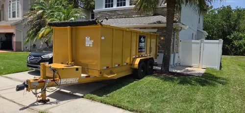 Champs dumpster angled with its trailer wheels resting on the grass edge to keep the Lake Mary sidewalk clear