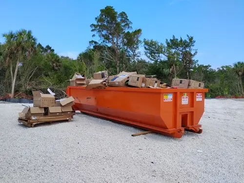 Orange Champs dumpster filled with cardboard on the Winter Springs commercial construction site