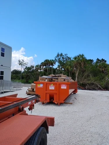 Loaded Champs dumpster on the gravel commercial lot beside the two story modular office trailers in Winter Springs