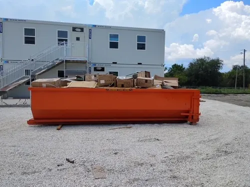 Champs dumpster filled with flattened boxes in front of the white modular office units in Winter Springs