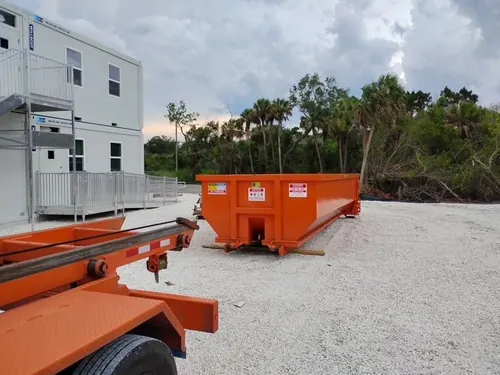Champs roll off trailer and dumpster on the Winter Springs commercial lot near the modular offices at dusk