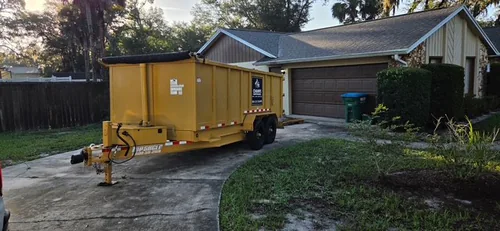 Champs dumpster set along the bend of a curved Winter Springs driveway with the garage still open