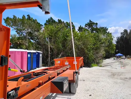 Empty Champs dumpster set on fresh limerock at the end of a row of portable toilets on a Eustis job site
