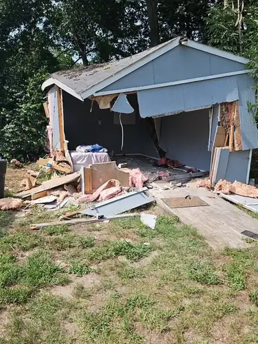 Champs crew tearing down a grey shed during a Eustis removal