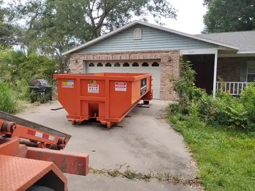 Side view of the Champs trailer and dumpster on the Ocoee driveway with overgrown beds crowding both edges