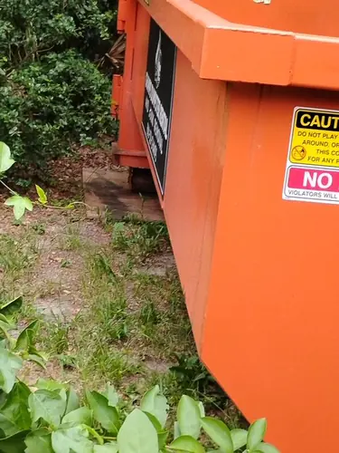 Close view of the wood panels laid flat under the left side of the Champs dumpster to spread its weight on soft grass