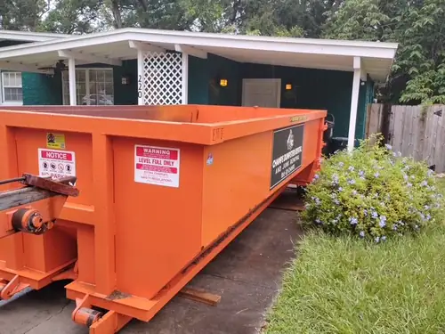 Champs dumpster rolled onto a Saint Cloud concrete driveway beside a green house with a white lattice carport post