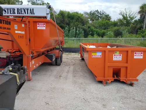Champs trailer alongside a dumpster already placed at the back fence line of the Winter Springs commercial yard